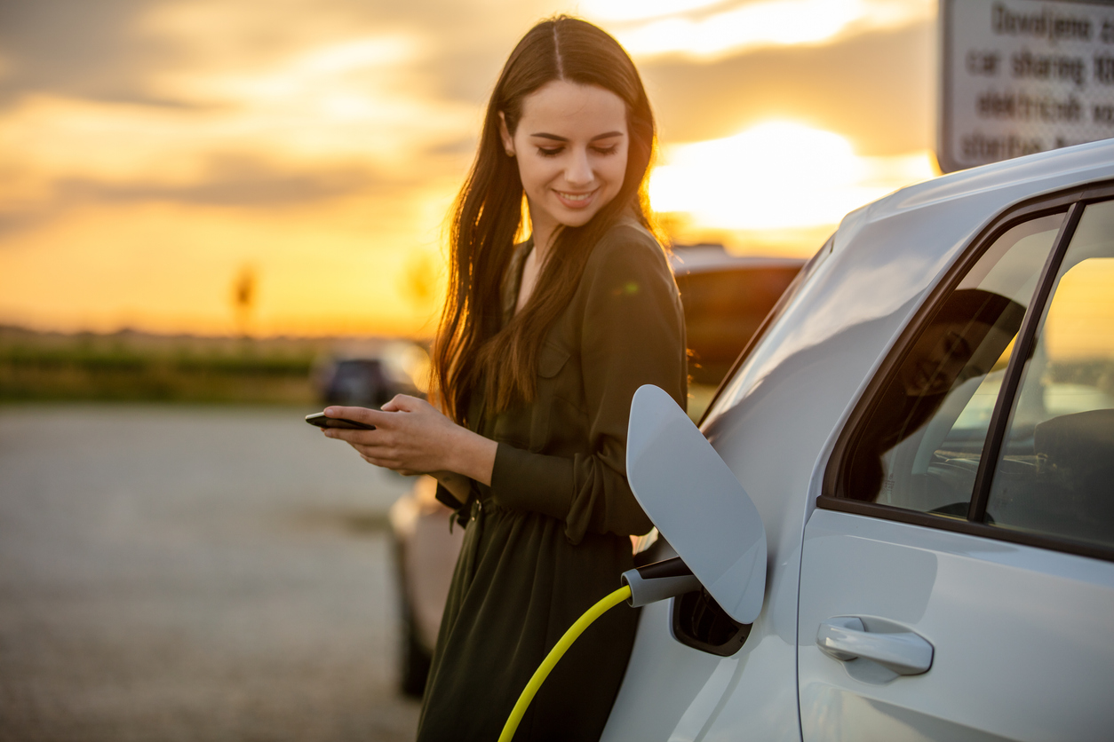 A woman charging her electric vehicle at an EV charging station