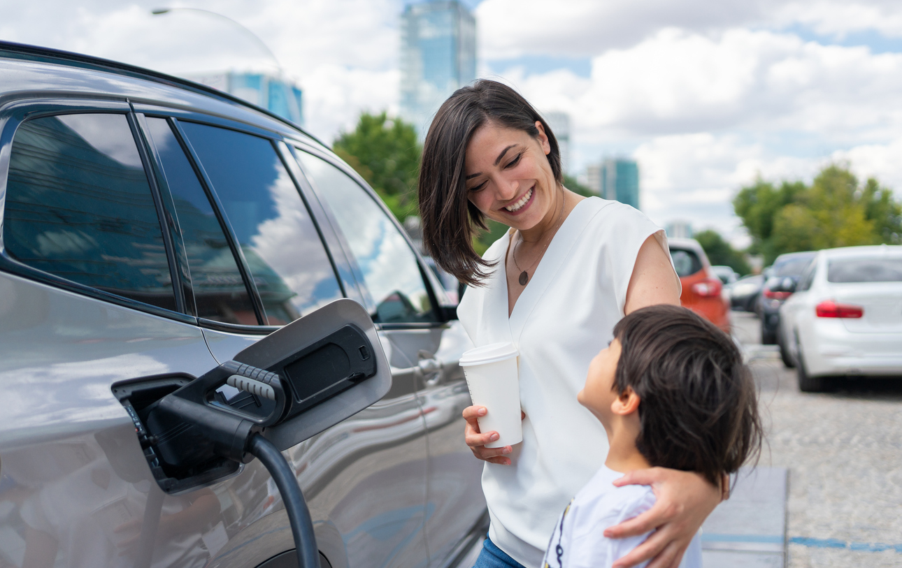 A woman and her child charging their electric vehicle at a public charging station