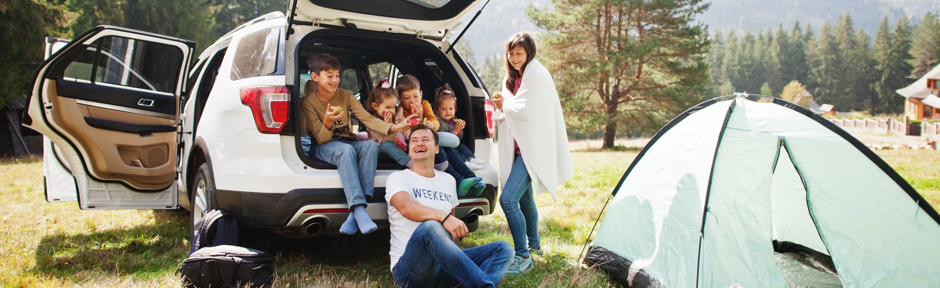 Family sitting around SUV, camping